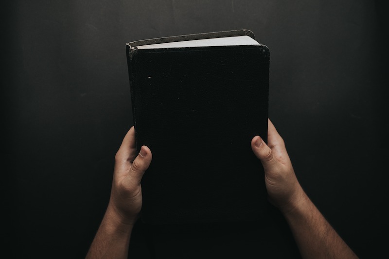 Man holding a black bible.